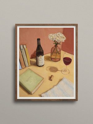 Framed artwork of a still life scene with books, a bottle, and a glass on a table.