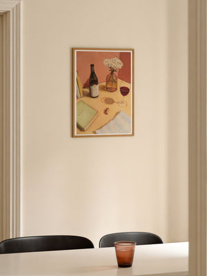 Framed artwork on a wall above a table with a glass.