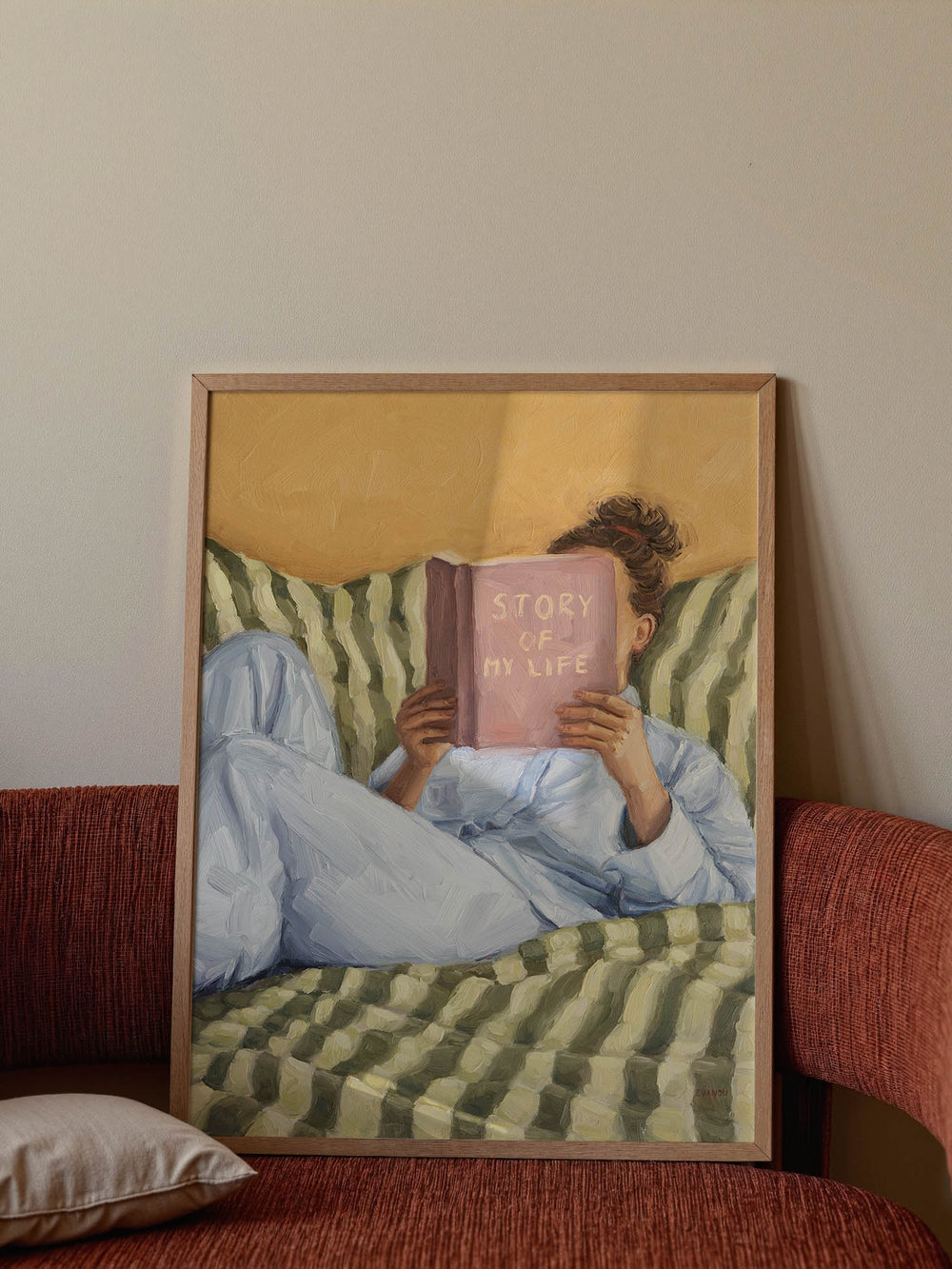 Person reading a book titled 'Story of My Life' on a striped couch.
