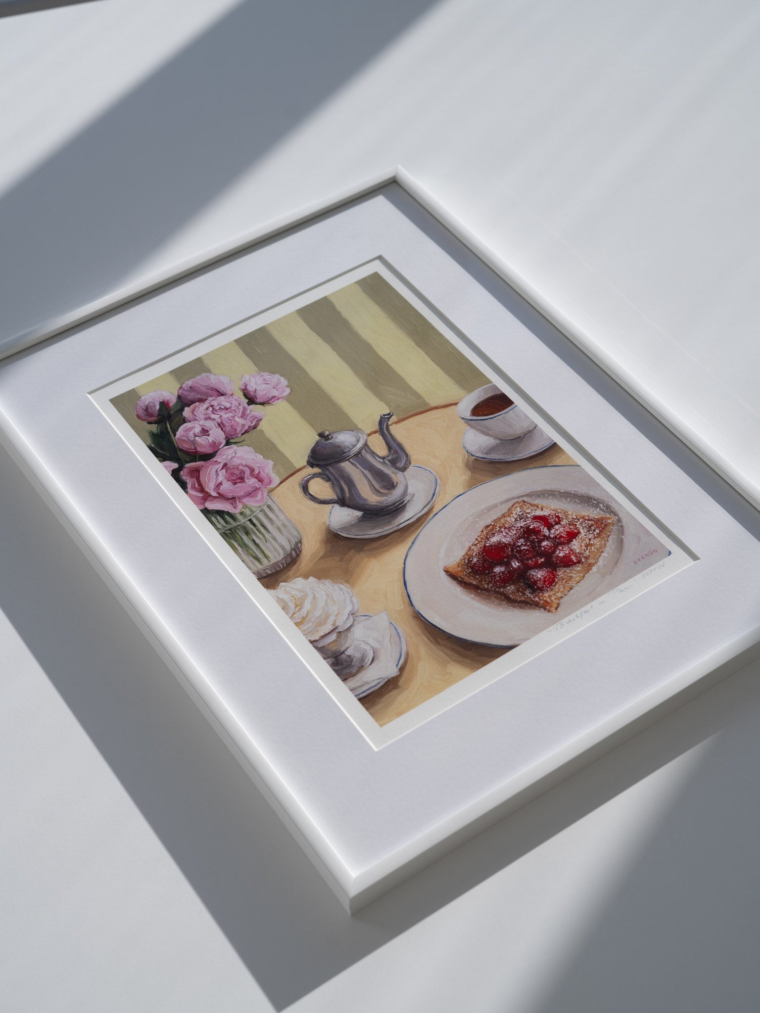 Framed art print featuring a table setting with a silver coffee pot, cup, whipped cream, crepe with strawberries, and peonies in a vase.