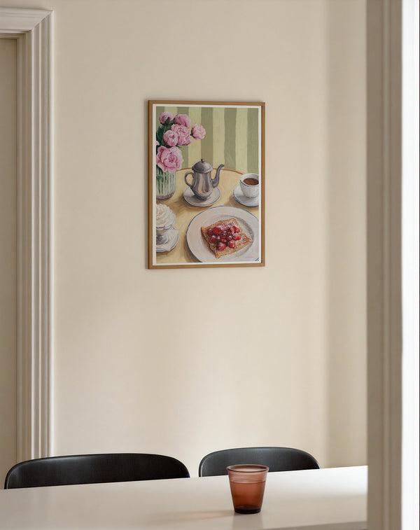 Framed art print featuring a table setting with a silver coffee pot, cup, whipped cream, crepe with strawberries, and flowers, hanging on a wall in the dining room