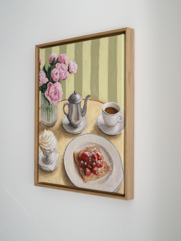 Framed artwork of a table setting with coffee, whipped cream, crepe with strawberries and flowers on a table, set against a striped background.