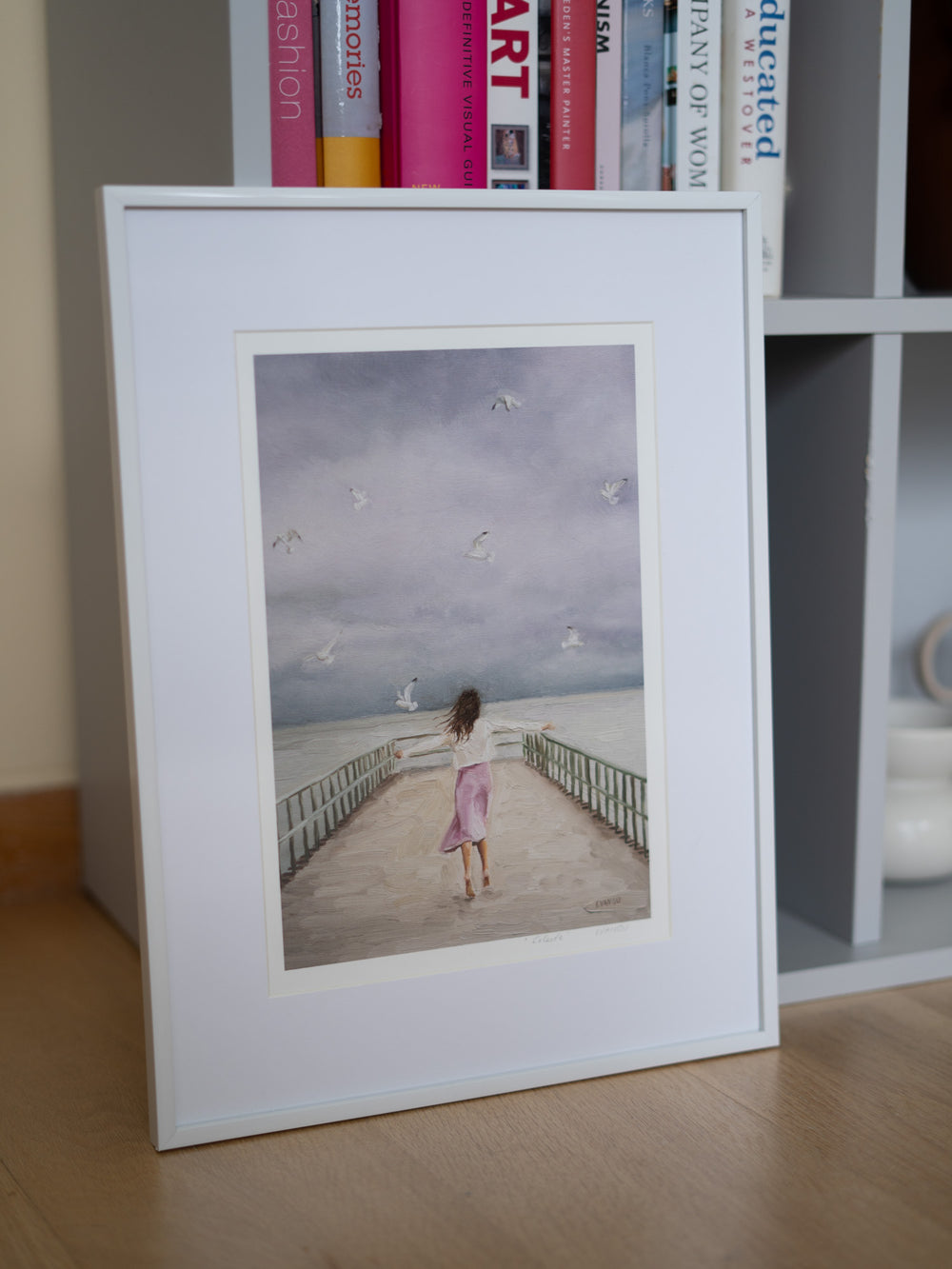 Art print of a woman on a pier with seagulls flying above.