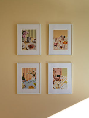 Four framed pictures featuring table scenes, hanging on a beige wall