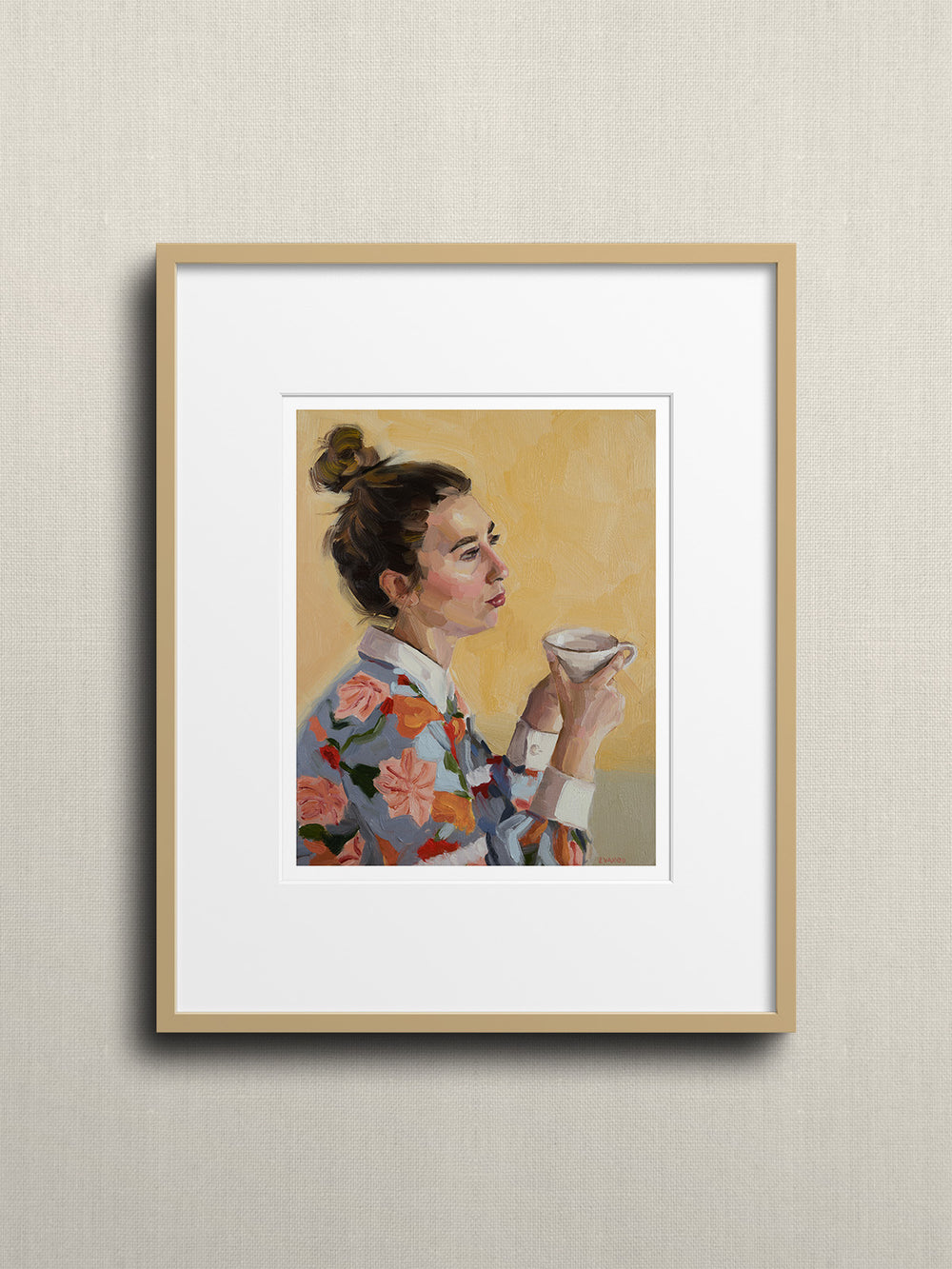 A woman, adorned in a vibrant floral shirt, sits comfortably with a cup of tea in her hands, savouring a moment of calm. 