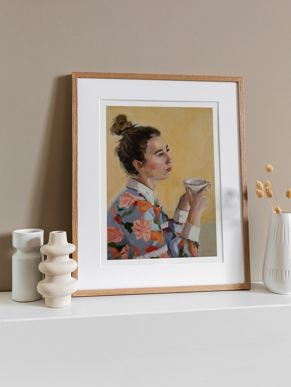 A woman, adorned in a vibrant floral shirt, sits comfortably with a cup of tea in her hands, savouring a moment of calm. 