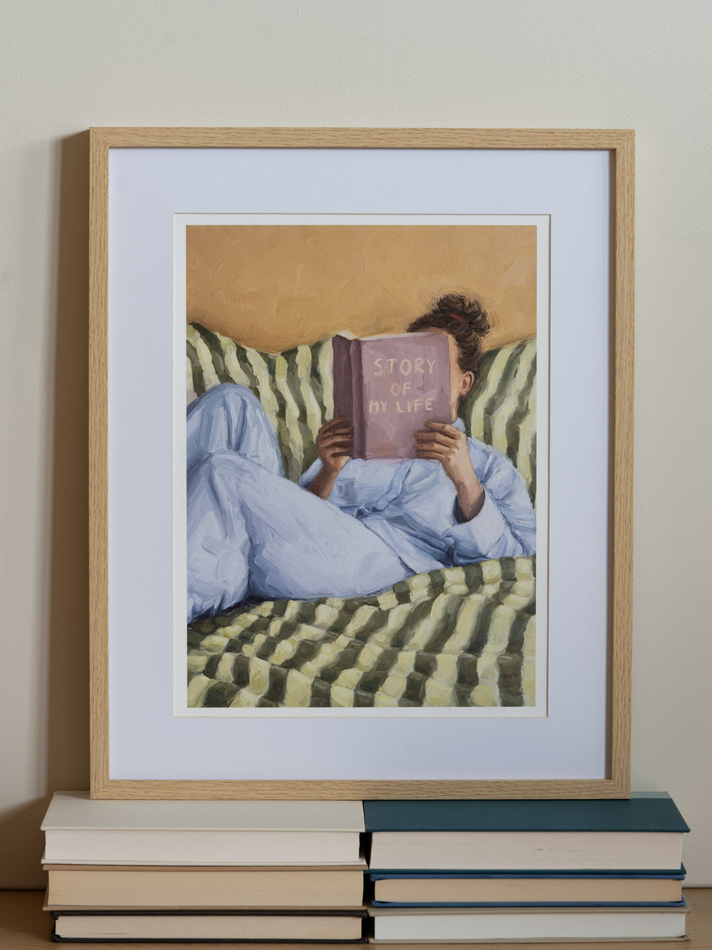 Person reading a book titled 'Story of My Life' on a striped couch.