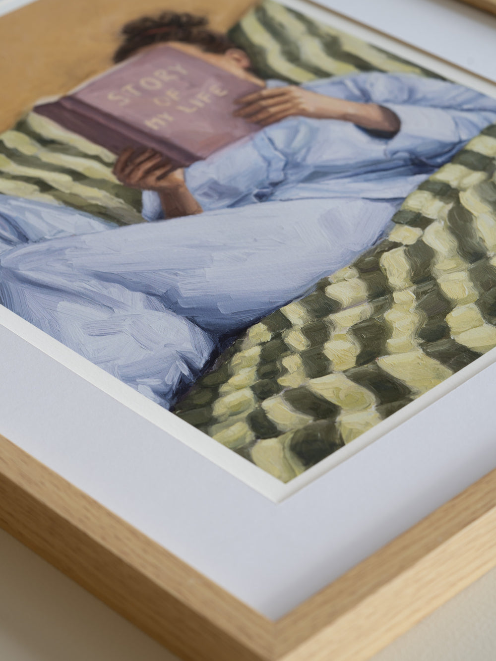Person reading a book titled 'Story of My Life' on a striped couch.