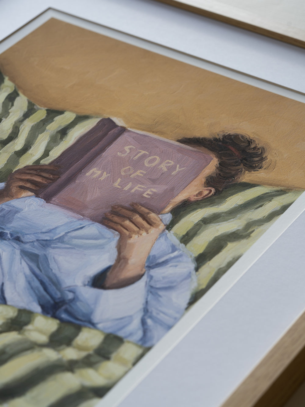 Person reading a book titled 'Story of My Life' on a striped couch.
